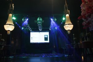 Salao de festas com lustres de cristal, globos espelhados, feixes de luz azul e verde e painel de LED montados pela Angelo Eventos